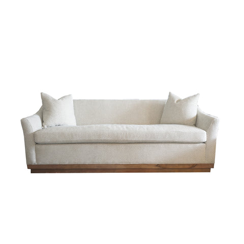 one cushion sofa in soft neutral green with wooden plinth base.