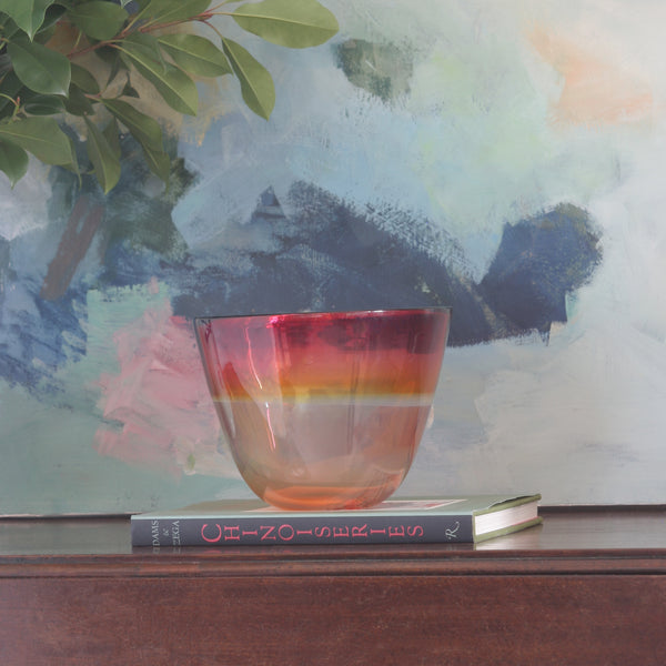 Mouth blown glass bowl in Red and Yellow in front of abstract painting